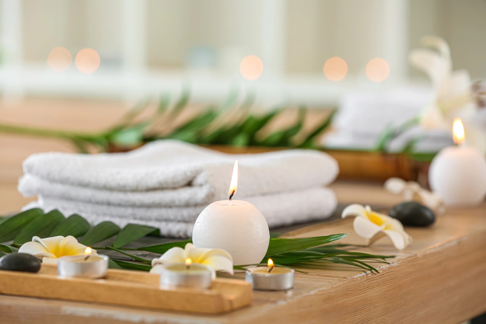 A calming, quiet massage room setup featuring a padded table with clean linens, professional massage oils, and ambient lighting.